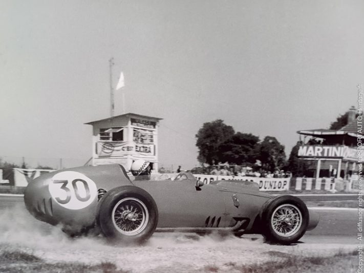 Jean Behra, hors de la piste, au volant de sa Ferrari D246 durant le Grand Prix de France, son dernier avec Ferrari. - Photo : Bernard Cahier