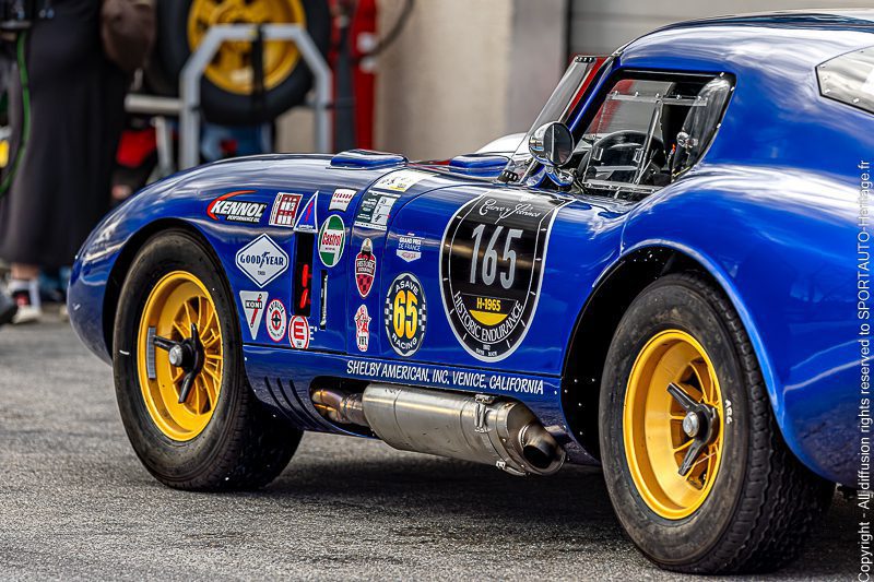 Voiture de course bleue avec des jantes jaunes et des autocollants sur la carrosserie.