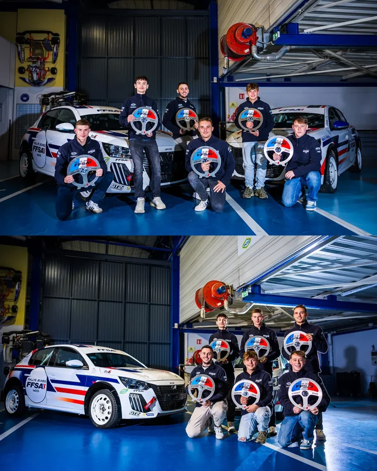 Groupe de jeunes pilotes de rallye posant avec des volants de course dans un garage automobile.