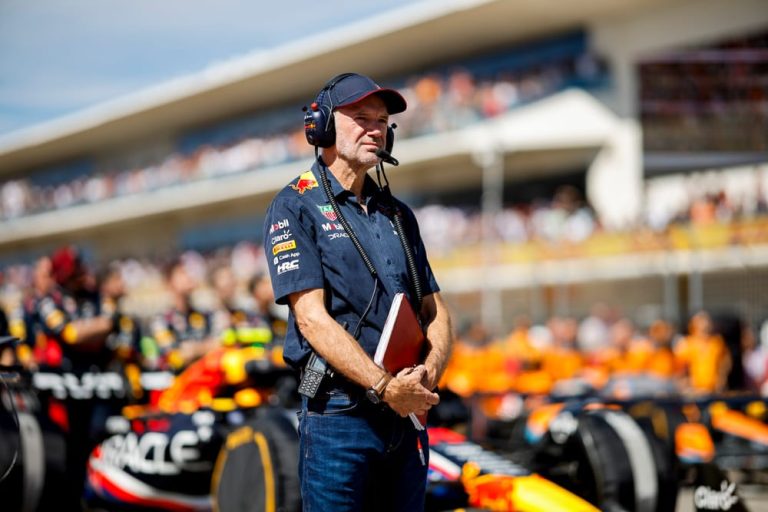 Un homme en tenue de l'équipe Red Bull Racing observant les voitures de course sur la grille de départ.