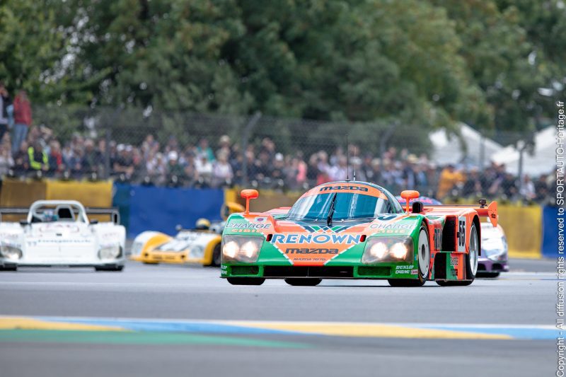 Voiture de course Mazda Renown participant à une course d'endurance, avec d'autres voitures en arrière-plan.