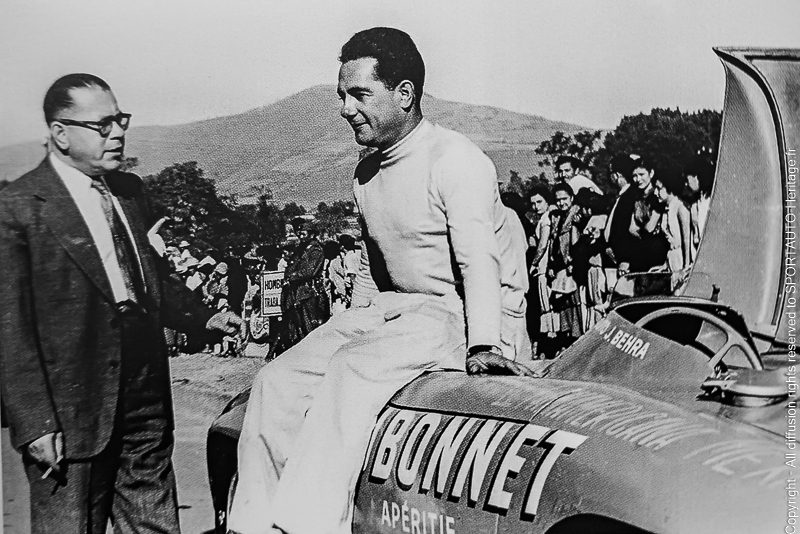 Jean Behra est assis sur sa Gordini sponsorisé par Dubonnet avant le départ d'une des étapes.