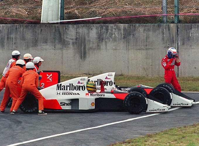 SUZAKA, JAPON : Le Brésilien Ayrton Senna reçoit une poussée de la part des commissaires de piste pour repartir, tandis que son coéquipier et grand rival français Alain Prost abandonne la course après leur collision dans une chicane lors du Grand Prix du Japon de Formule 1 à Suzuka, le 22 octobre 1989. Senna a franchi la ligne d'arrivée en tête mais a été disqualifié par la suite, accusé d'avoir bénéficié d'une poussée illicite de la part des commissaires et d'avoir coupé la chicane. PHOTO AFP TOSHIFUMI KITAMURA (Crédit photo : TOSHIFUMI KITAMURA/AFP/Getty Images)